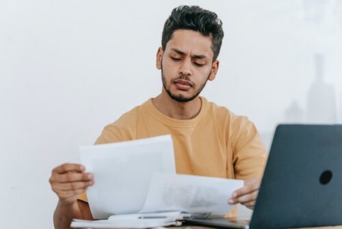 man looking at documents in front of computer