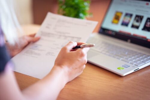 woman at laptop looking at paper
