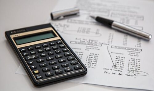 calculator, pen, and paper with numbers